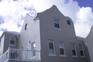 uma grande casa branca com uma cerca branca em Cavendish Heights Suites em Pembroke