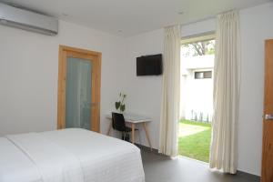 a bedroom with a bed and a desk and a television at Kaleo Hotel Boutique in San Salvador