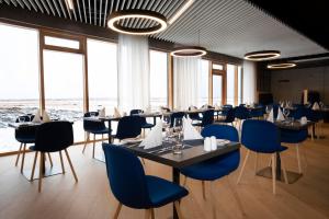 un comedor con mesas, sillas azules y ventanas en Landhotel en Hella