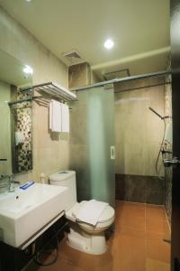 uma casa de banho com um WC, um lavatório e um chuveiro em Transera Hotel Pontianak em Pontianak