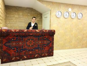 a man standing behind a counter with clocks on the wall at La Casa Sahil in Baku