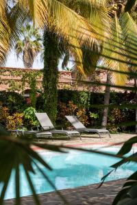 two lounge chairs sitting next to a swimming pool at Posada del Molino in Todos Santos