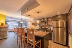 cocina con nevera y mesa con sillas en Copperstone Resort - Mountain View 2 Bedroom Condo en Canmore