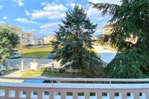 a white fence and a pine tree on a street at Art decor luxury apartment in Komotini