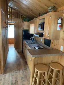 una cocina con armarios de madera, fregadero y taburetes en Bearlodge Mountain Resort, en Sundance