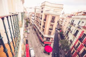 una via cittadina con edifici e un ombrello rosso di Hostal Sol Los Angeles a Madrid