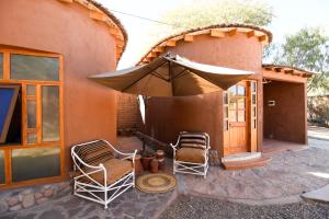 a patio with two chairs and an umbrella at Hostal y Cabañas Renta House San Pedro in San Pedro de Atacama