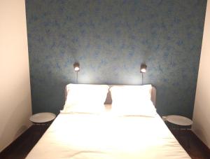 a bed with two white pillows and a blue wall at Appartement rénové 2 chambres centre historique in Bordeaux