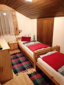 a bedroom with two beds with red sheets at Haus Johanna in Sankt Jakob in Defereggen