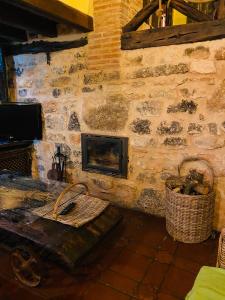 Casa rural La Antigua Vaqueria في Aguilera: غرفة معيشة مع جدار حجري مع موقد