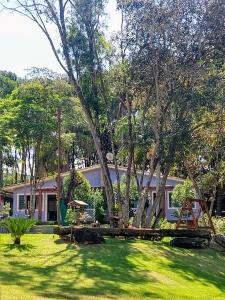 a house with a yard with green grass and trees at Pousada Villa das Águas,chalés com Ar condicionado e um rio no quintal in Monte Alegre do Sul