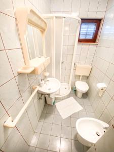 a white bathroom with a sink and a toilet at Apartman Zorka in Povlja