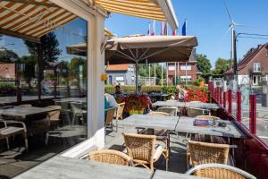 un patio con mesas, sillas y una sombrilla en Vivaldi Hotel, en Westerlo