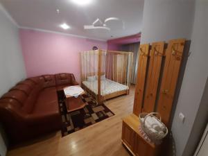ein Wohnzimmer mit einem Sofa und einem Kinderbett in der Unterkunft Лагуна in Snyatyn