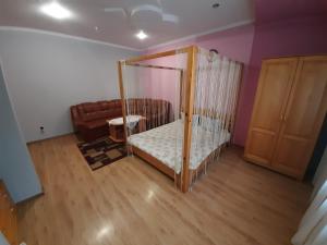ein Schlafzimmer mit einem Kinderbett und einem Sofa in einem Zimmer in der Unterkunft Лагуна in Snyatyn