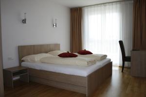 a bedroom with a large bed with white sheets and red pillows at Da Yang in Rankweil