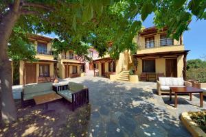 a park with benches and a tree in front of a building at Alkifron Hotel in Kala Nera