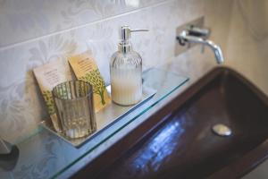 a bathroom sink with a soap bottle on a glass shelf at Piazza Duomo Deluxe in Cecina