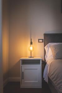 a lamp on a night stand next to a bed at Piazza Duomo Deluxe in Cecina
