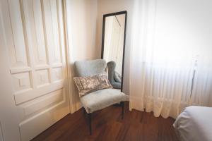 a bedroom with a chair in front of a mirror at Piazza Duomo Deluxe in Cecina