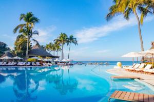 a swimming pool with palm trees and the ocean at Grand Velas Riviera Nayarit in Nuevo Vallarta