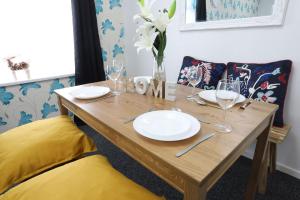 a wooden table with plates and wine glasses on it at B'ham NEC/Airport/HS2 Short Stay in Birmingham