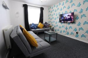 a living room with a couch and a tv on the wall at B'ham NEC/Airport/HS2 Short Stay in Birmingham