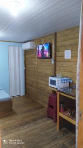 Habitación con TV y cocina con paredes de madera. en Belo Mar, en Penha