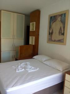 Un dormitorio con una cama blanca con una foto en la pared en Le Loup Residência para Hospedagem Suítes 1, en Blumenau