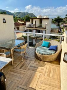 balcón con muebles de mimbre, mesa y sillas en Casa de boneca em Condomínio - Juquehy, en São Sebastião