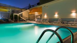 a swimming pool at night with chairs and tables at Copthorne Downtown by Millennium in Abu Dhabi