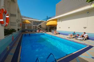 a pool at a hotel with people sitting around it at Copthorne Downtown by Millennium in Abu Dhabi
