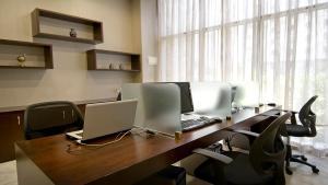 an office with a desk with a laptop and chairs at Copthorne Downtown by Millennium in Abu Dhabi