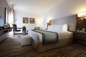 a hotel room with a large bed and a desk at Copthorne Downtown by Millennium in Abu Dhabi