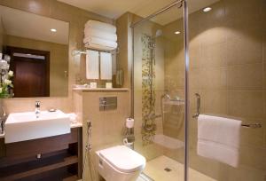 a bathroom with a shower and a toilet and a sink at Copthorne Downtown by Millennium in Abu Dhabi
