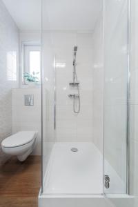 a white bathroom with a shower and a toilet at Marittimo Resort in Świnoujście