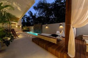 a patio with a bed and a swimming pool at El Brujo Tulum in Tulum