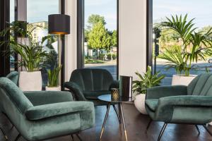 a waiting room with green chairs and plants at Holiday Inn Berlin City Center East Prenzlauer Berg, an IHG Hotel in Berlin