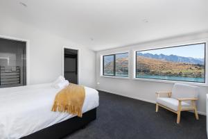 Un dormitorio con una cama y una silla y ventanas. en Alpine Retreat - Panoramic Views, en Queenstown