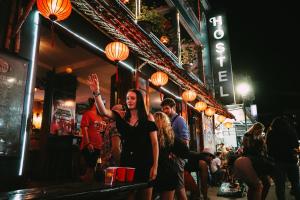 a woman standing in a bar with her hand in the air at Vietnam Backpacker Hostels - Hue in Hue