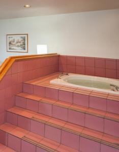 une baignoire jacuzzi dans une chambre revêtue de carrelage rose dans l'établissement Super 8 by Wyndham Salmon Arm, à Salmon Arm
