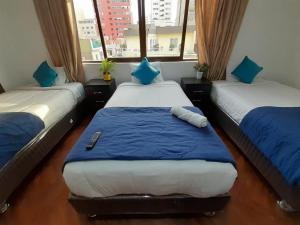 a room with three beds with blue and white sheets at APARTMENT FOR GROUP Miraflores in Lima
