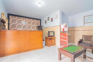 een kamer met een bureau, een tv en een tafel bij RedDoorz Syariah @ Tambak Mekar Street Subang in Rancadaleg