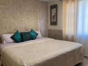 1 dormitorio con 1 cama con almohadas verdes y moradas en Departamento Bahia, en Ensenada