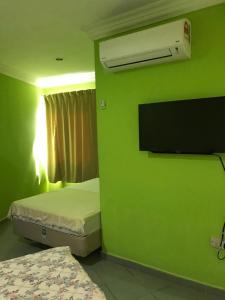a room with two beds and a green wall at Hotel Cahaya in Tanjung Malim