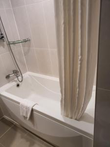 een badkamer met een bad en een douchegordijn bij Hotel Skypark Jeju 1 Newly renovated in Jeju-stad