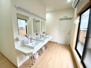 a bathroom with three sinks and two mirrors at Upper Hotel Ryogoku in Tokyo