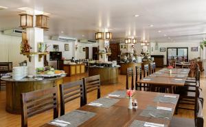 un ristorante con tavoli e sedie in legno e una cucina di Phowadol Resort And Spa a Chiang Rai