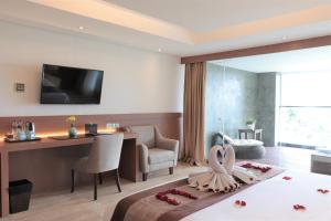 a hotel room with a bed and a desk and a television at de Vins Sky Hotel Seminyak in Seminyak