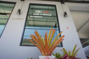 a sign in a building with a plant in front of it at SC Residences in Surat Thani